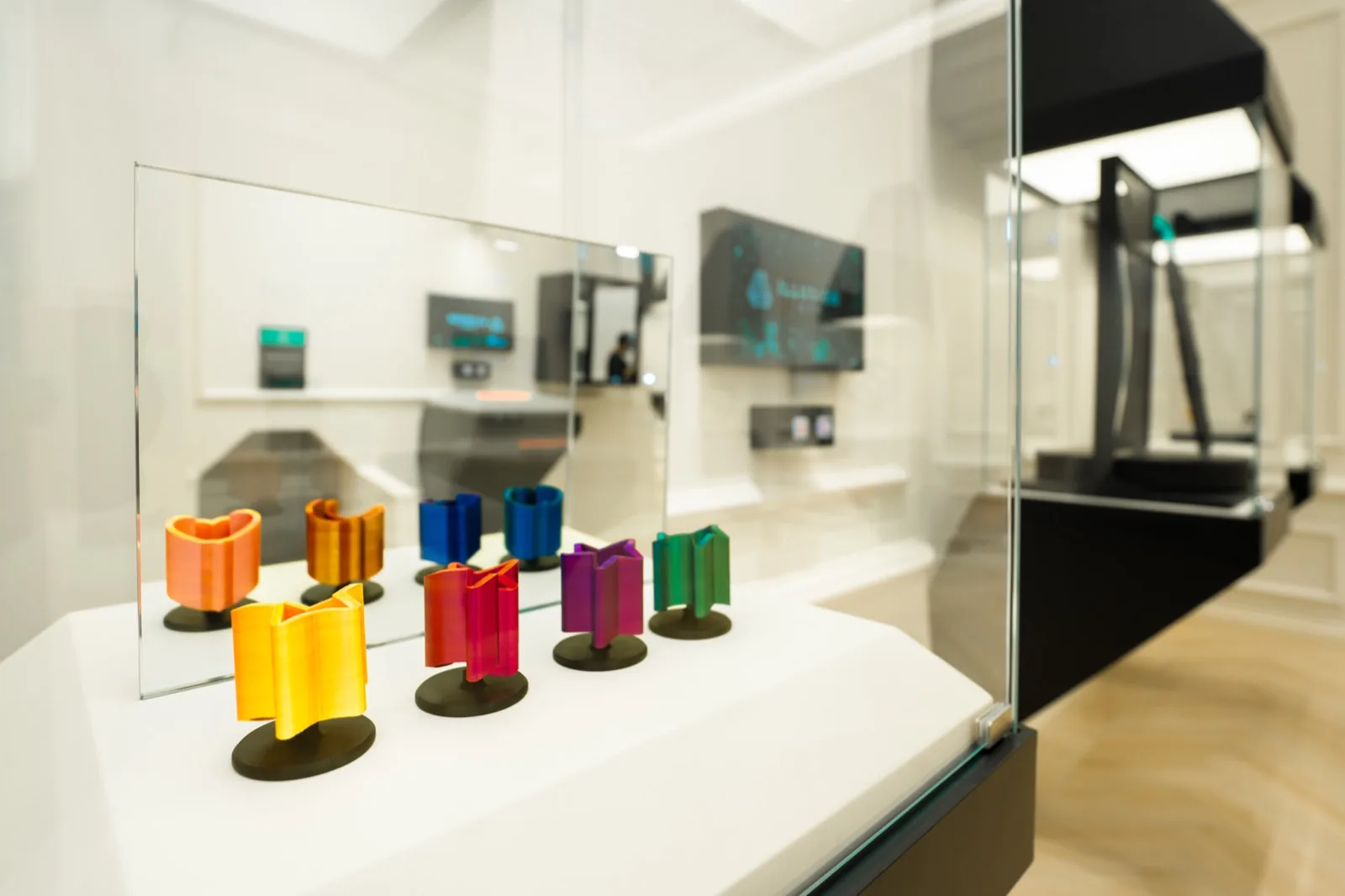 Gallery display with colorful 3D objects and interactive exhibits in a bright, minimalist museum space.
