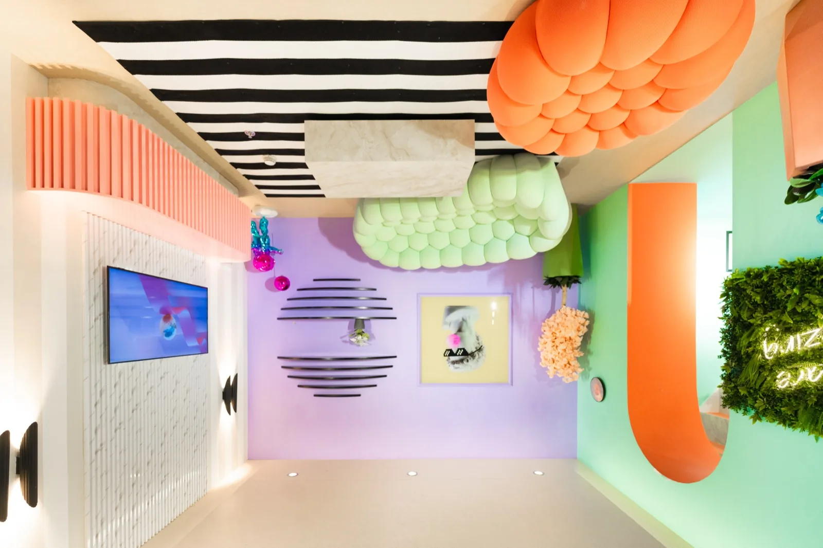 Colorful illusion museum interior with striped ceiling, pom-pom decorations, and purple-green walls
