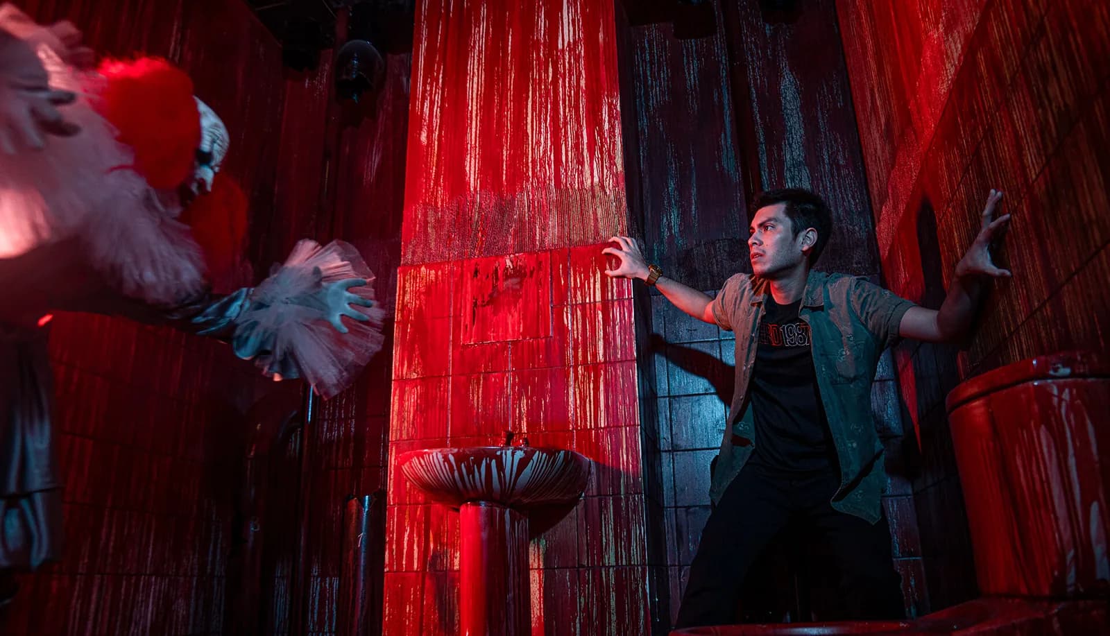 Actor performing in horror-themed room with red lighting and theatrical set design