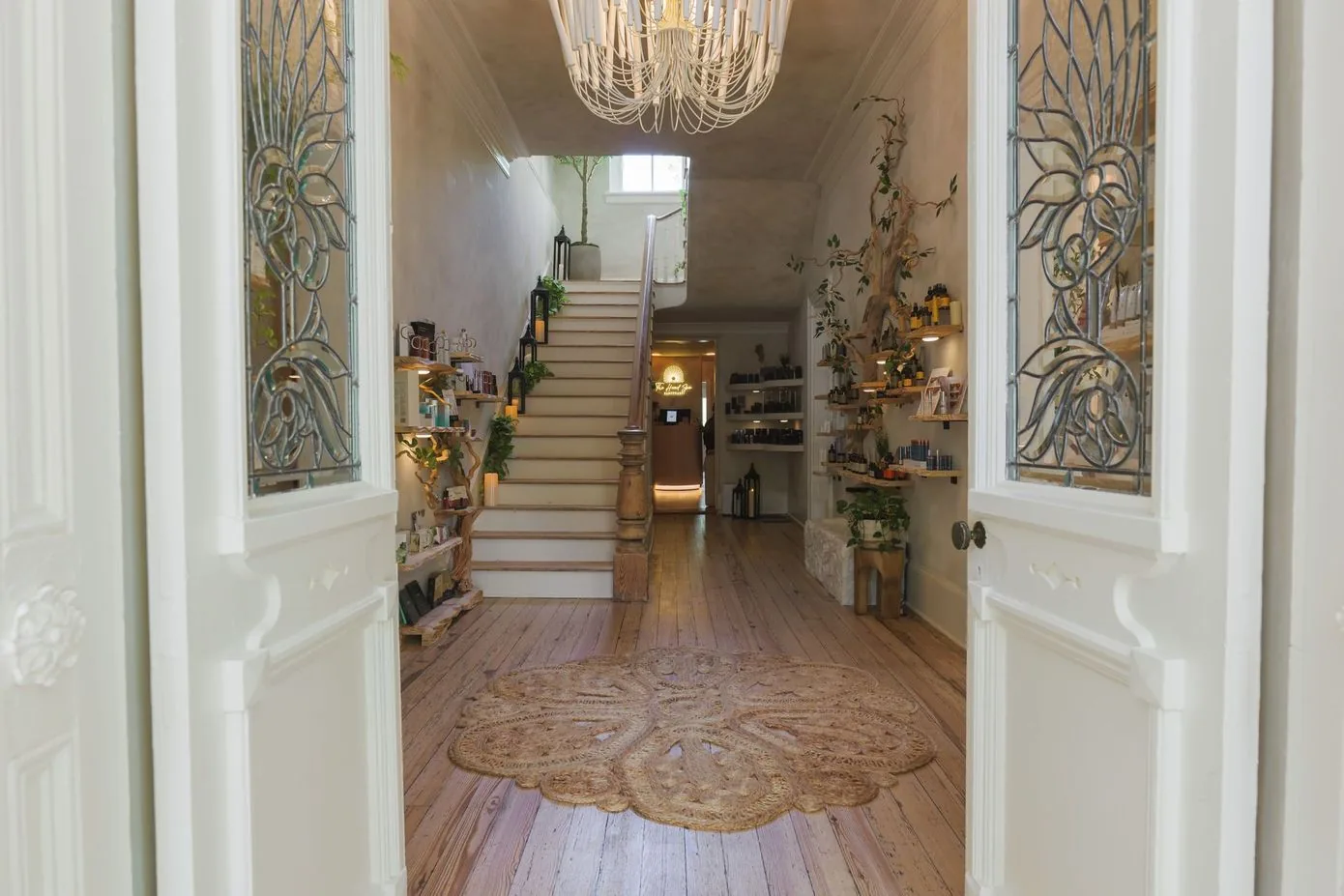 Spa entrance hallway with wooden floors, decorative doors, plants, and staircase with ambient lighting