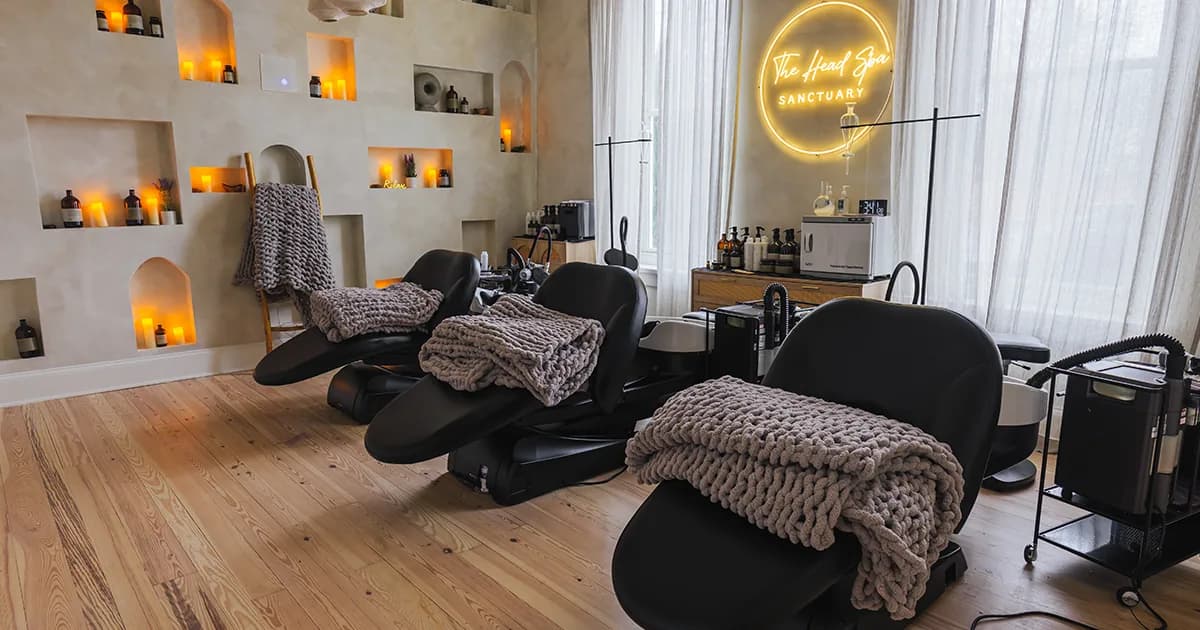 Spa treatment room with three black massage chairs, neon signage, and warm ambient lighting