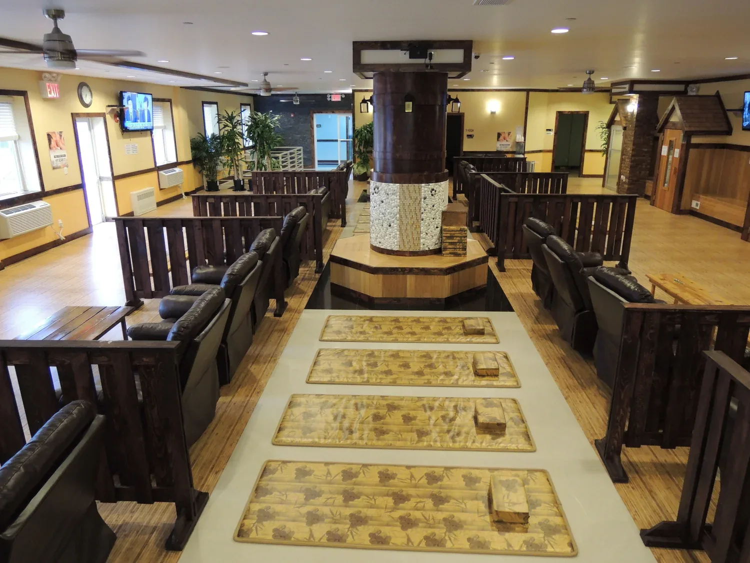Spa lobby with dark wood railings, leather seating, yellow walls, and central decorative column