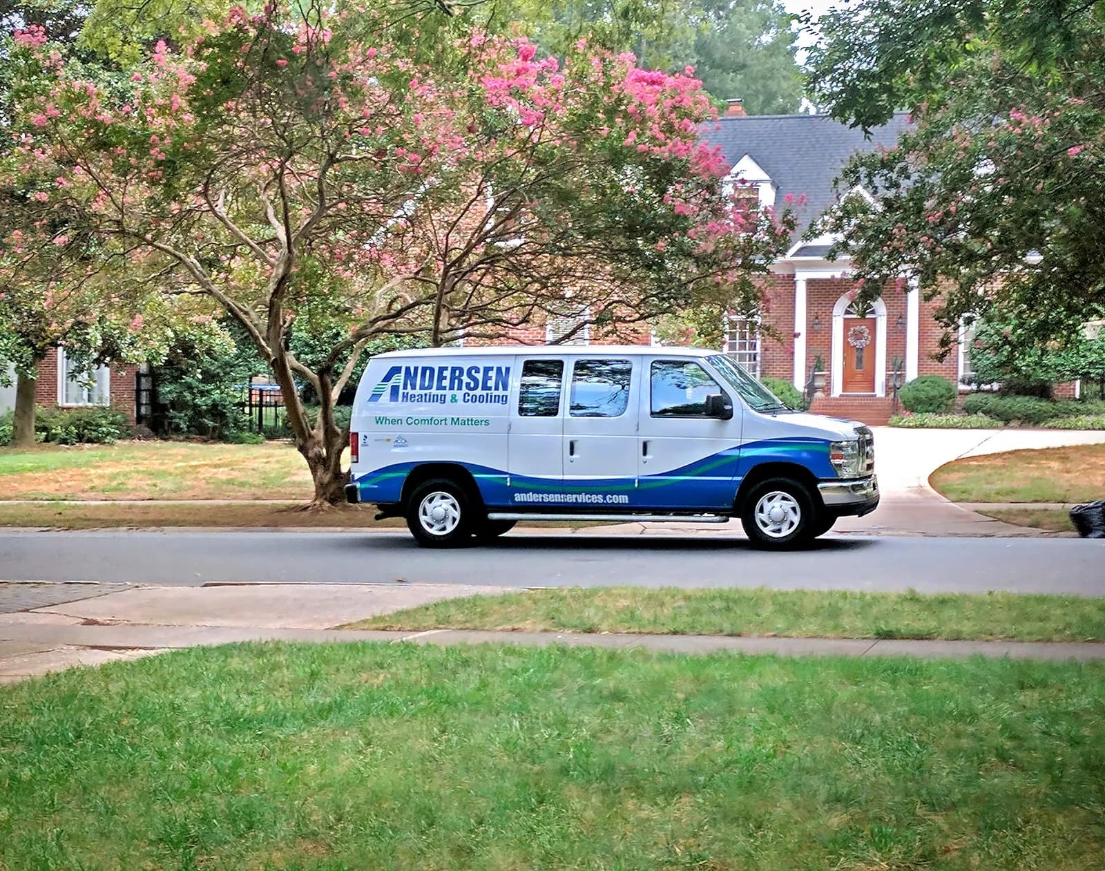 White and blue Andersen Heating & Cooling service van on residential street