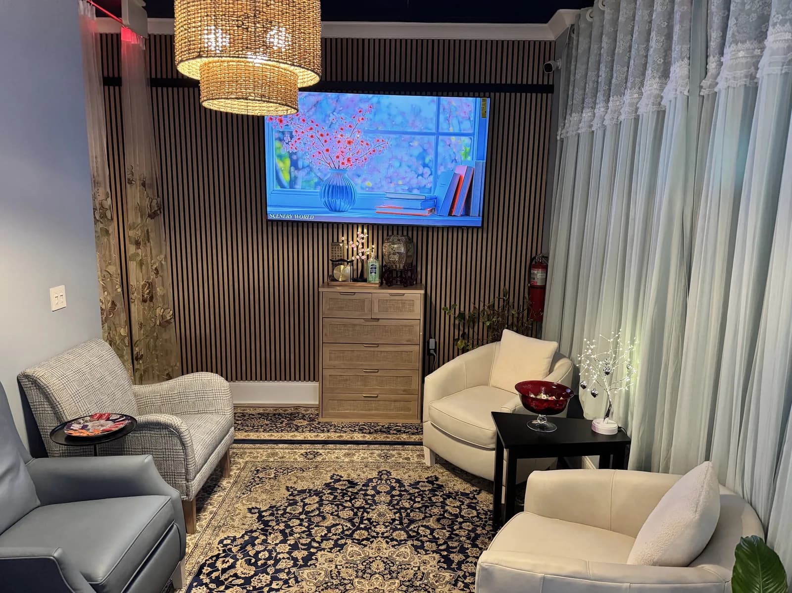 Spa lounge with cream-colored chairs, woven pendant light, and decorative blue artwork on wall-mounted screen.