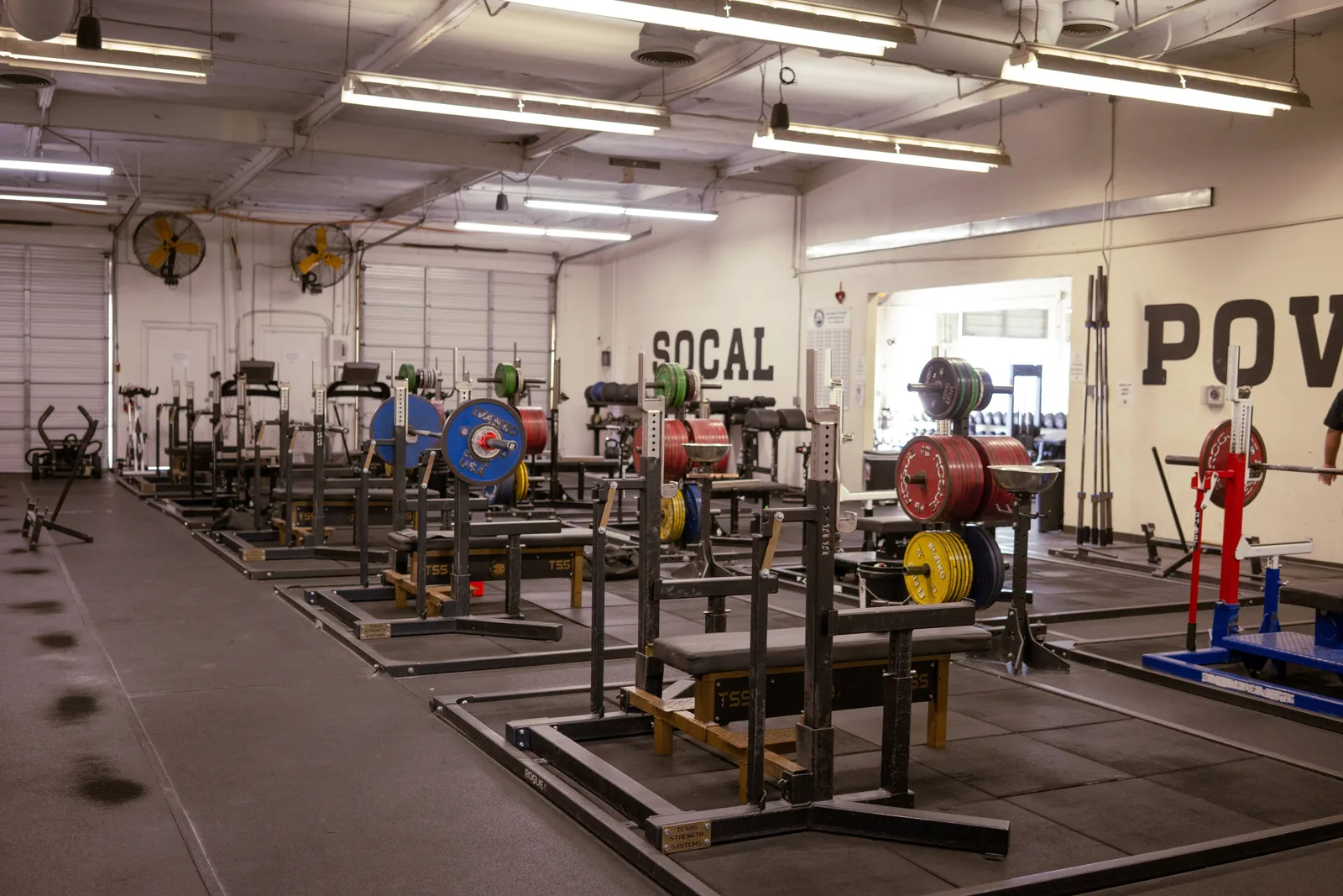Interior of SoCal Powerlifting gym with multiple lifting platforms, barbells, and weight plates