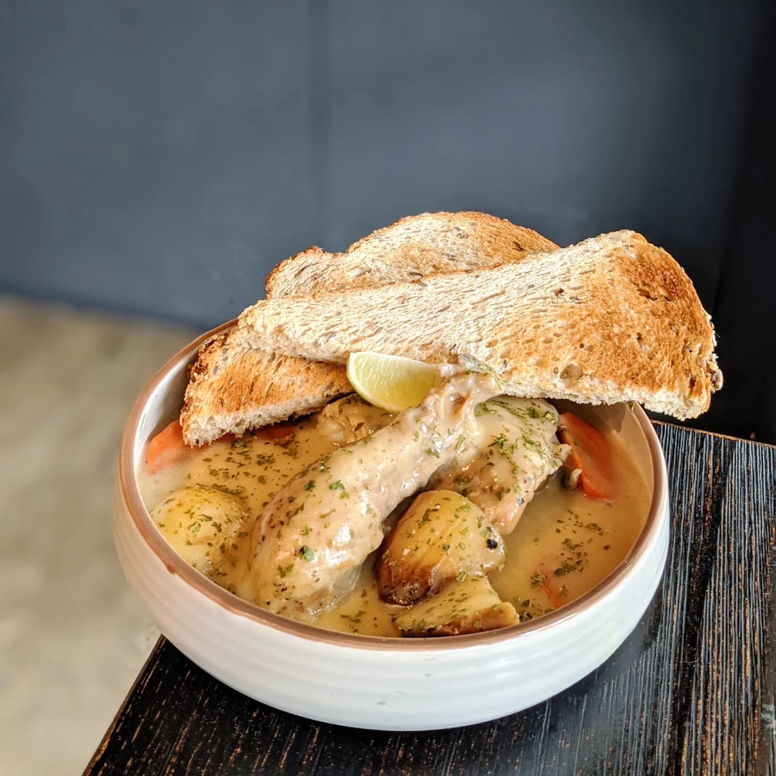 Toasted seeded bread sandwich filled with shrimp and tomato, served with herb-crusted potatoes in a creamy sauce