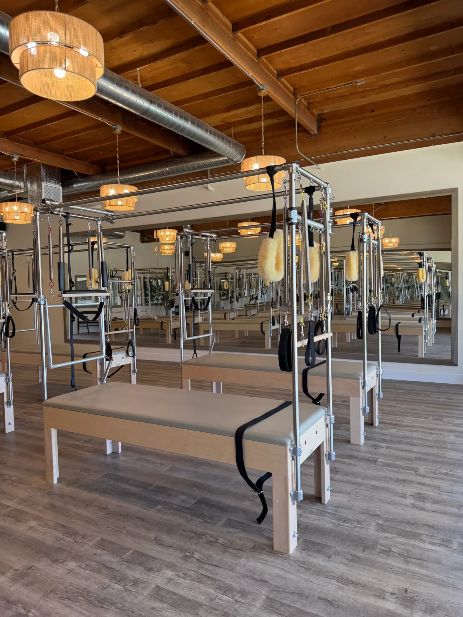 Pilates Reformer machines in a bright studio with wooden beams and pendant lights