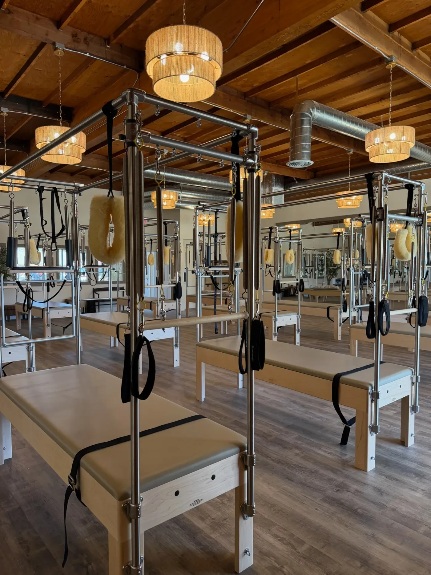 Pilates studio interior with reformer machines, wooden beams, and pendant lighting