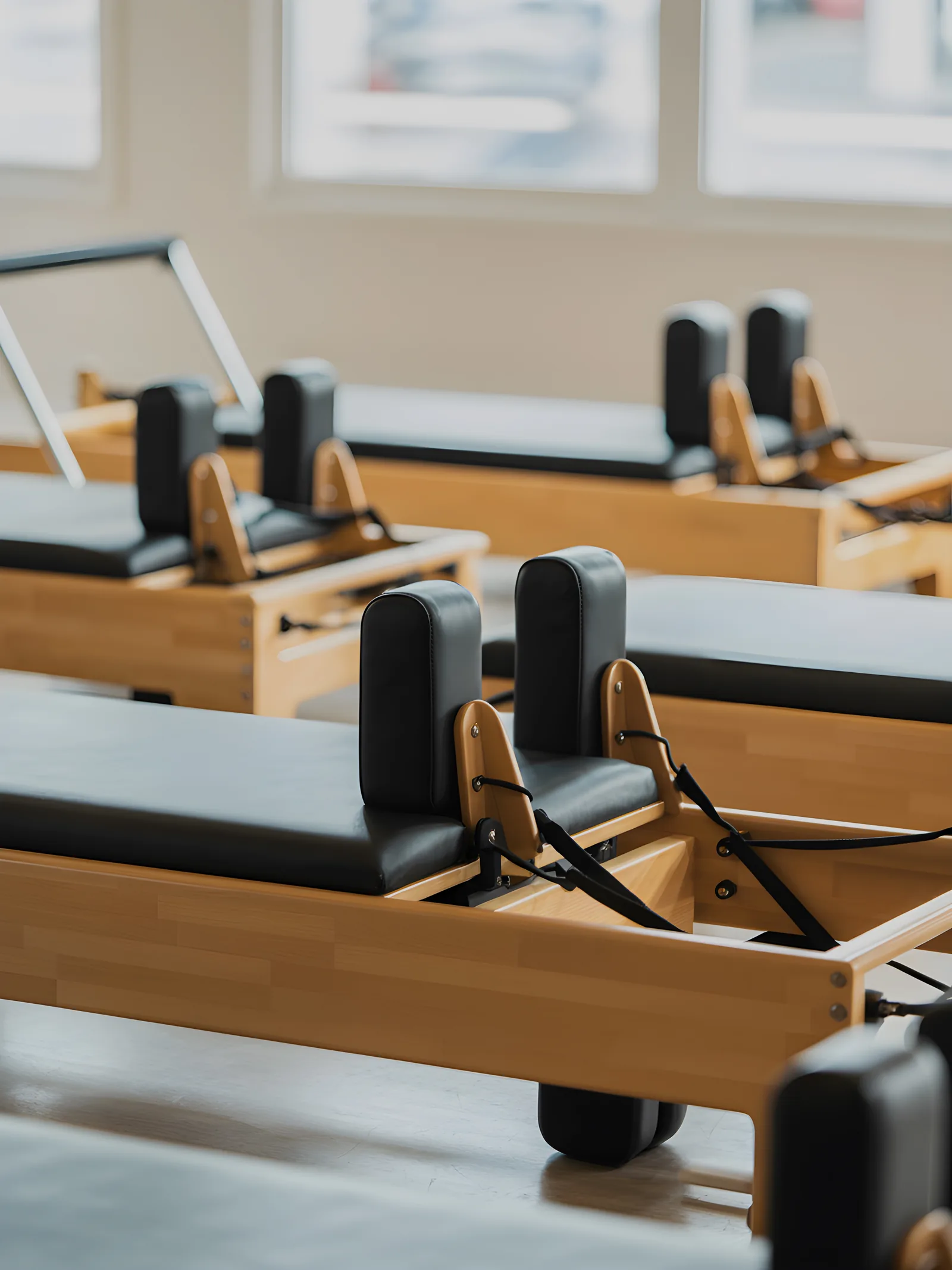 Pilates reformer machines lined up in a bright studio with large windows