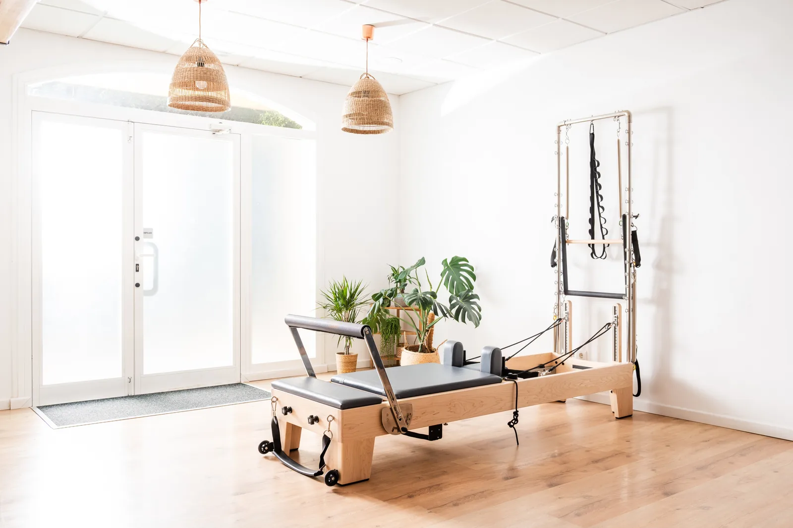 Pilates studio with reformer machine, plants, and modern minimalist decor