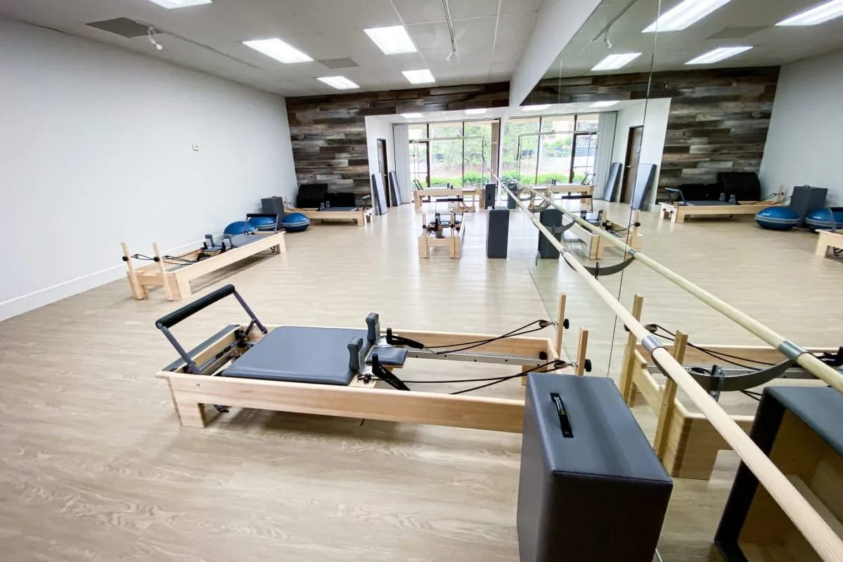 Pilates studio interior with reformer machines, mirrors, and bright windows