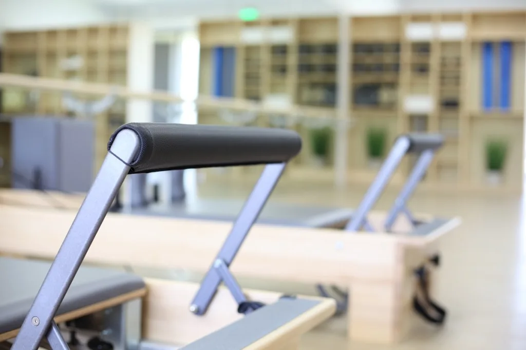 Pilates reformer machines in a light-filled studio with city views through windows