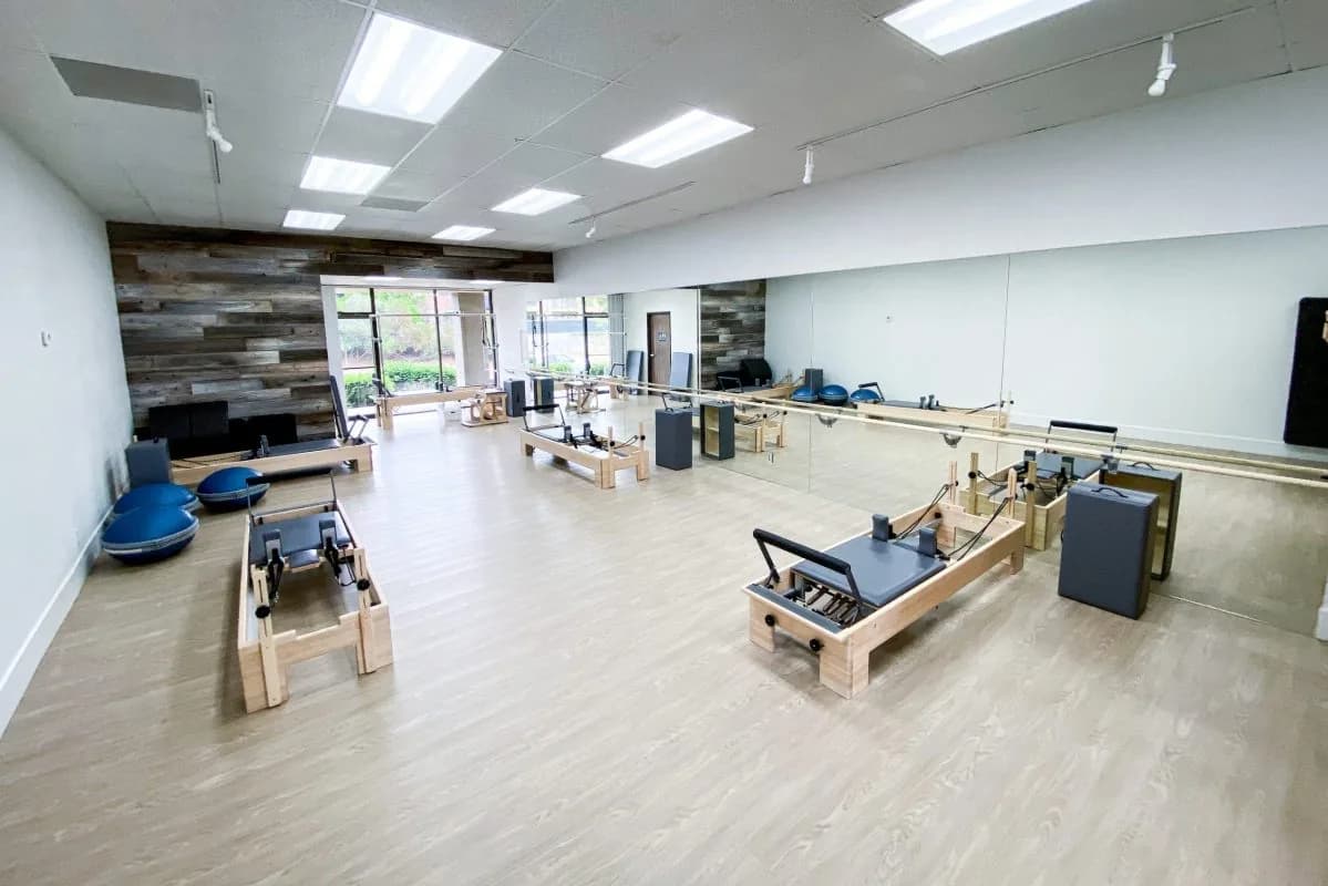Spacious pilates studio with reformer machines, mirrors, and natural lighting
