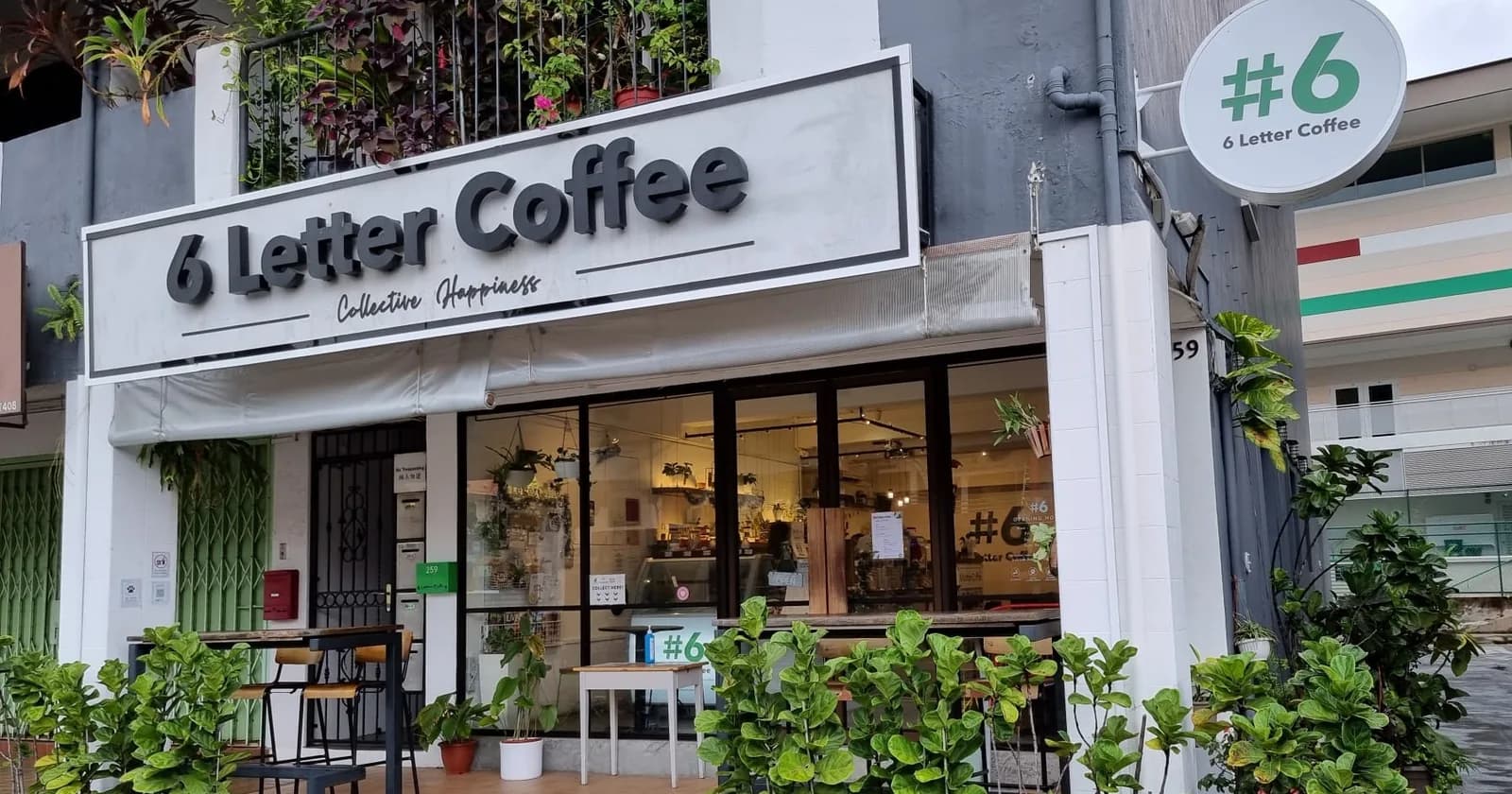 6 Letter Coffee storefront with white exterior, large signage, and green potted plants at the entrance