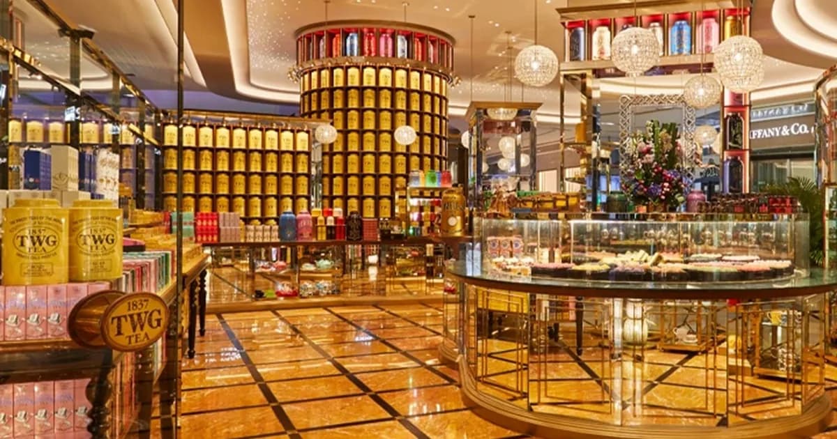 TWG Tea showroom interior with stacked yellow tea containers, crystal chandeliers, and product displays