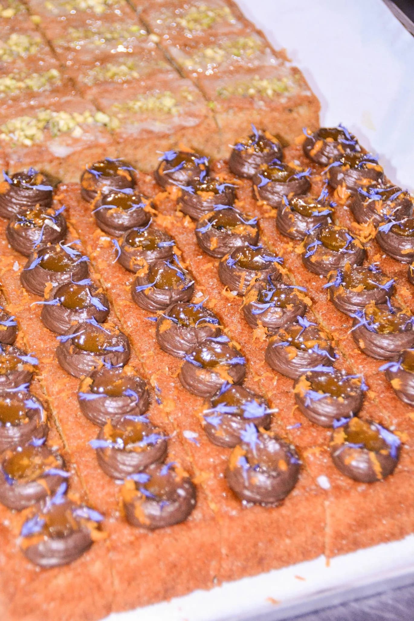 Decorated pastries with chocolate swirls, purple and gold edible glitter, and embellishments on orange base