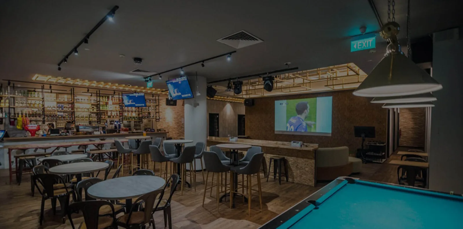Karaoke lounge interior with tables, bar area, pool table, and video screens