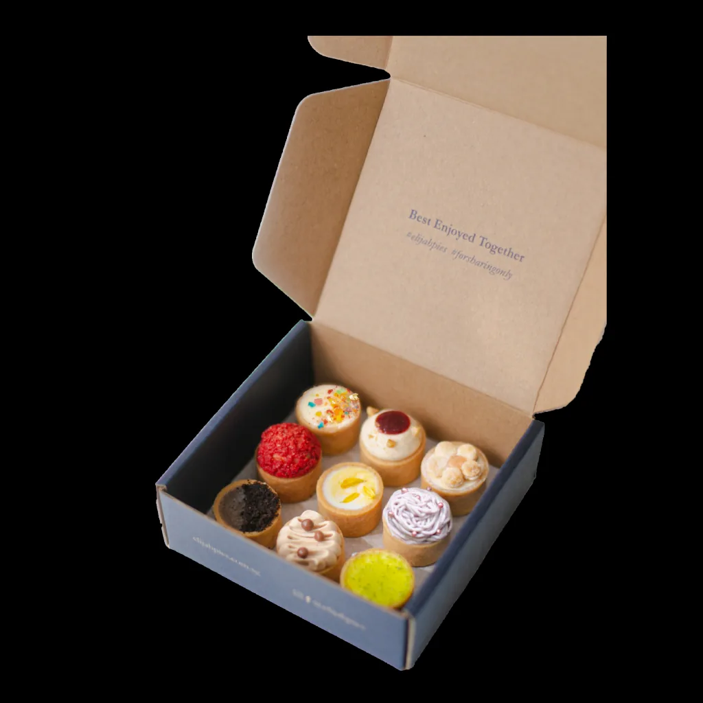 Open box displaying nine assorted decorated cupcakes with colorful frostings and toppings