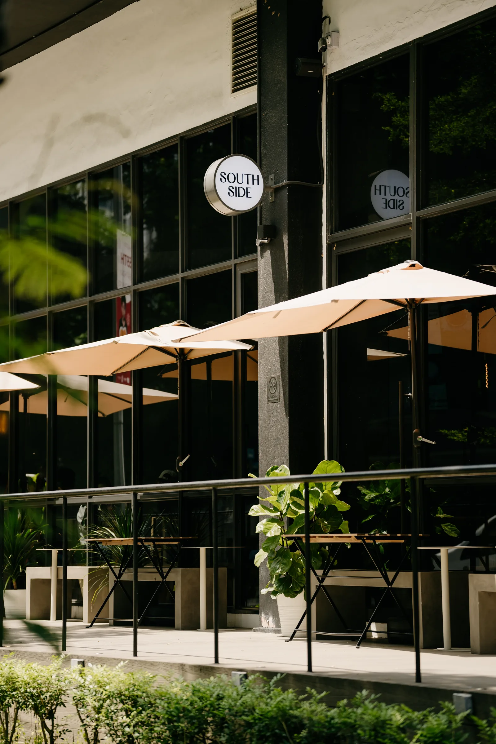 Restaurant exterior patio with shade umbrellas, metal railing, and large windows