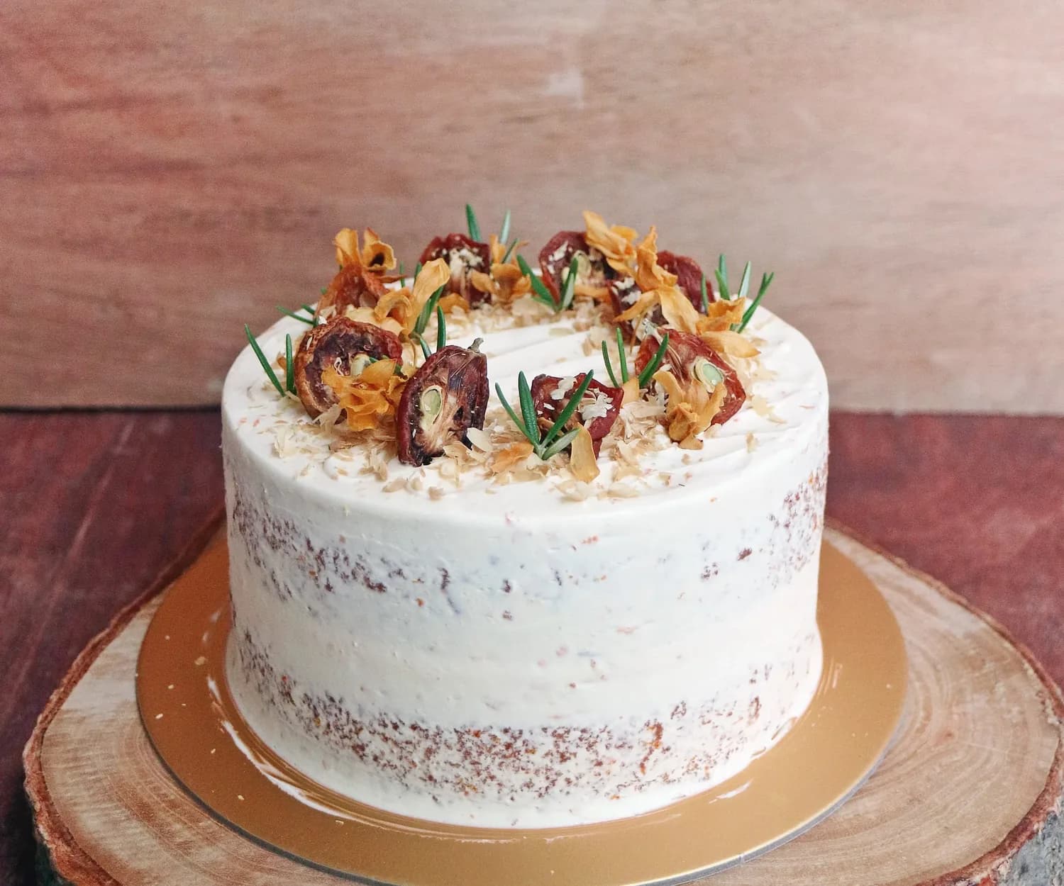 White layer cake with crispy fried garnishes, edible flowers, and chive sprouts on gold base