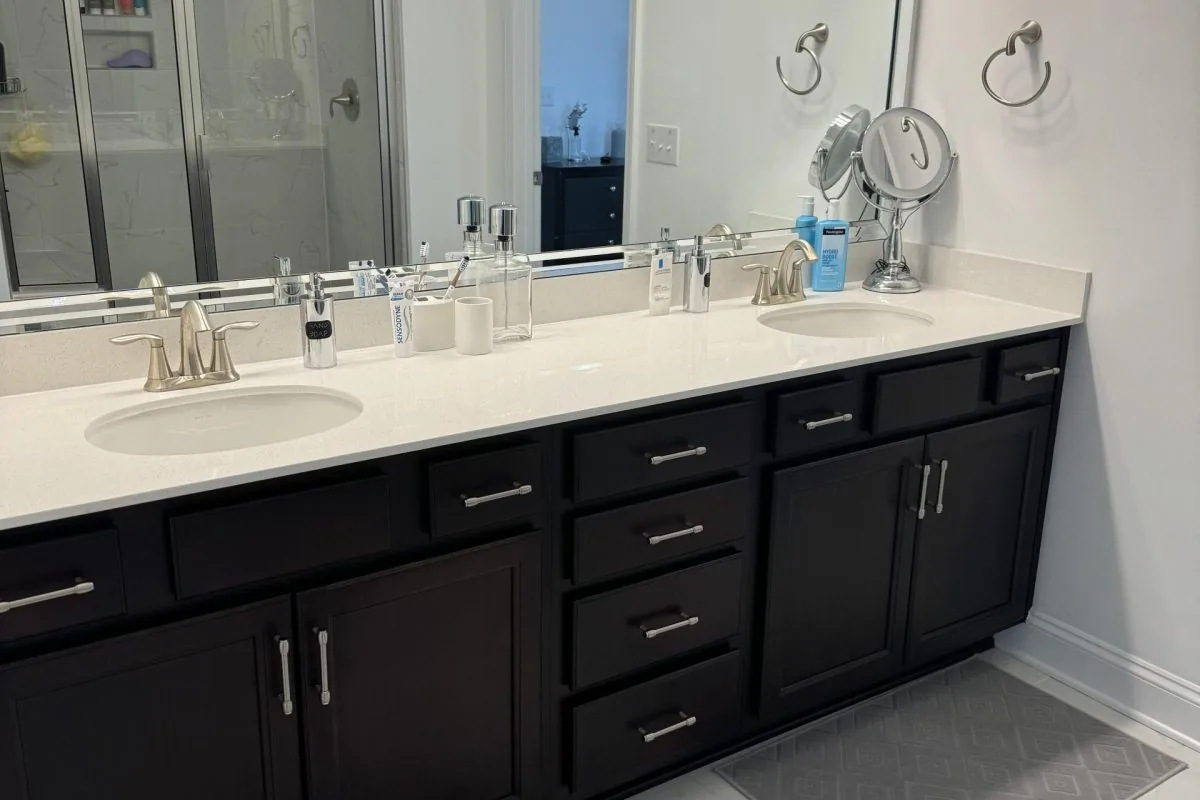 Clean modern bathroom with black vanity, white countertop, and dual sinks