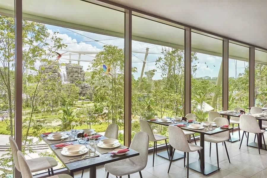 Dining tables set for service with garden views through large windows