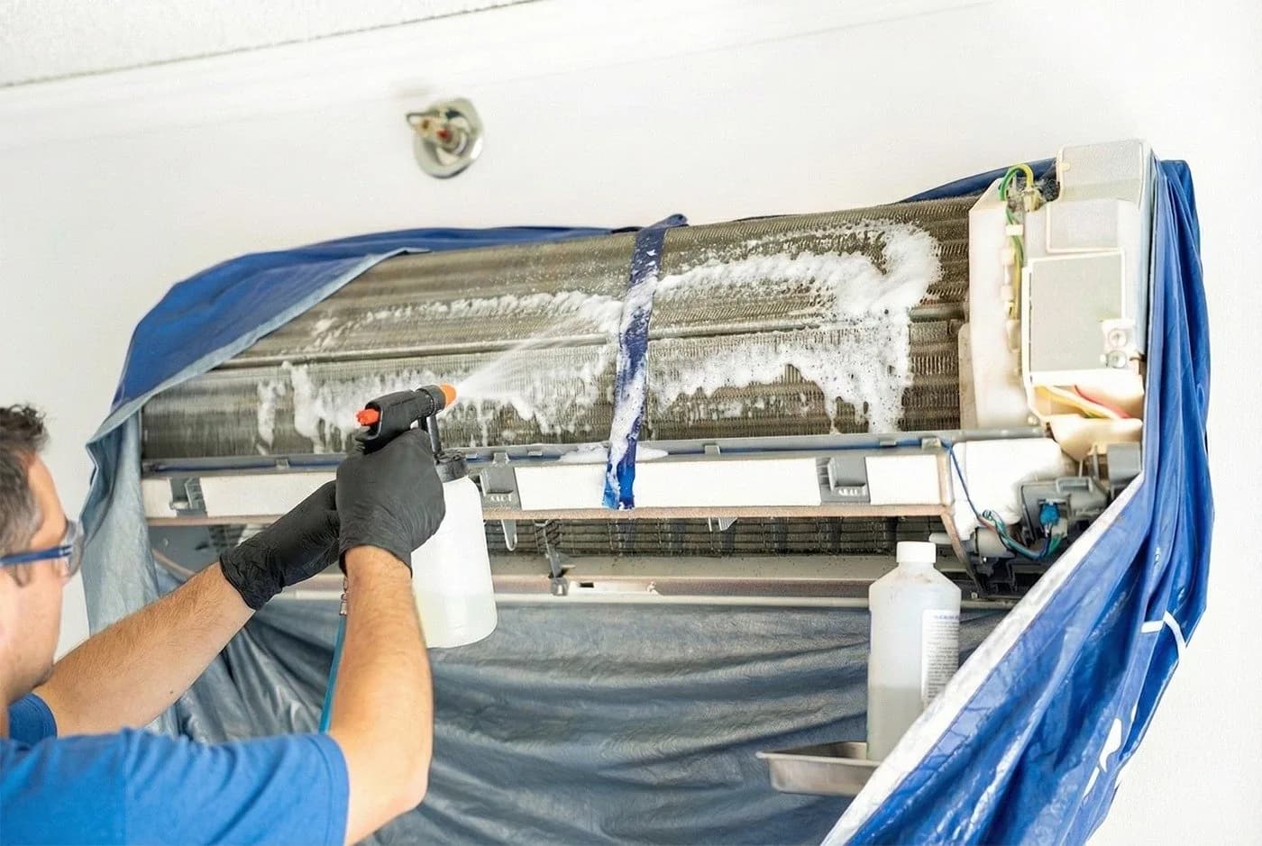 Technician cleaning air conditioner coils and fins during service maintenance