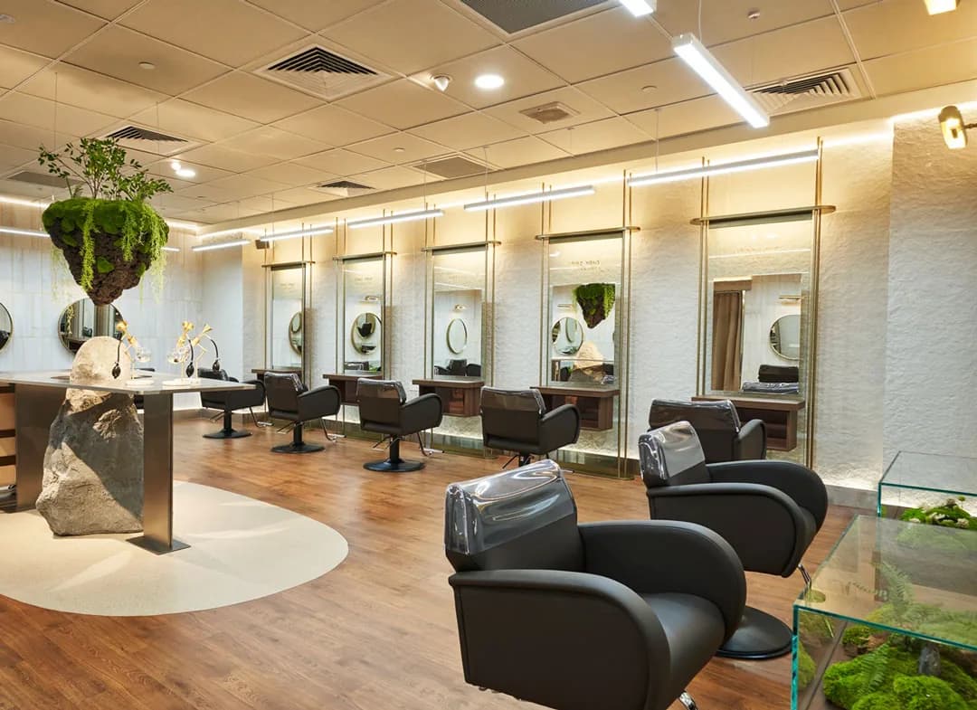 Modern hair salon interior with multiple styling stations, mirrored walls, and contemporary furnishings