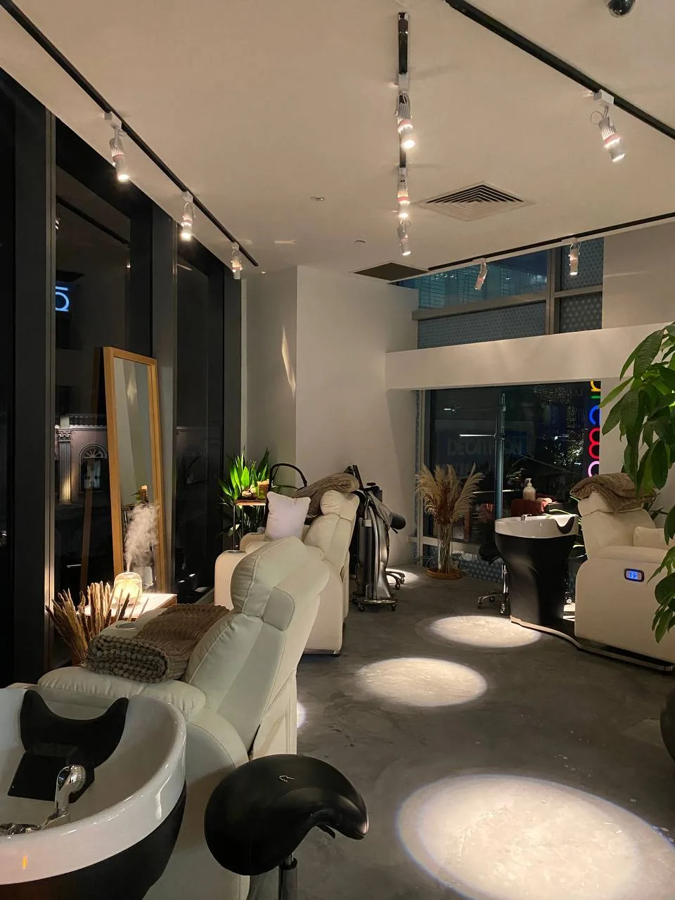 Modern head spa salon interior with white treatment chairs, ambient lighting, and plants