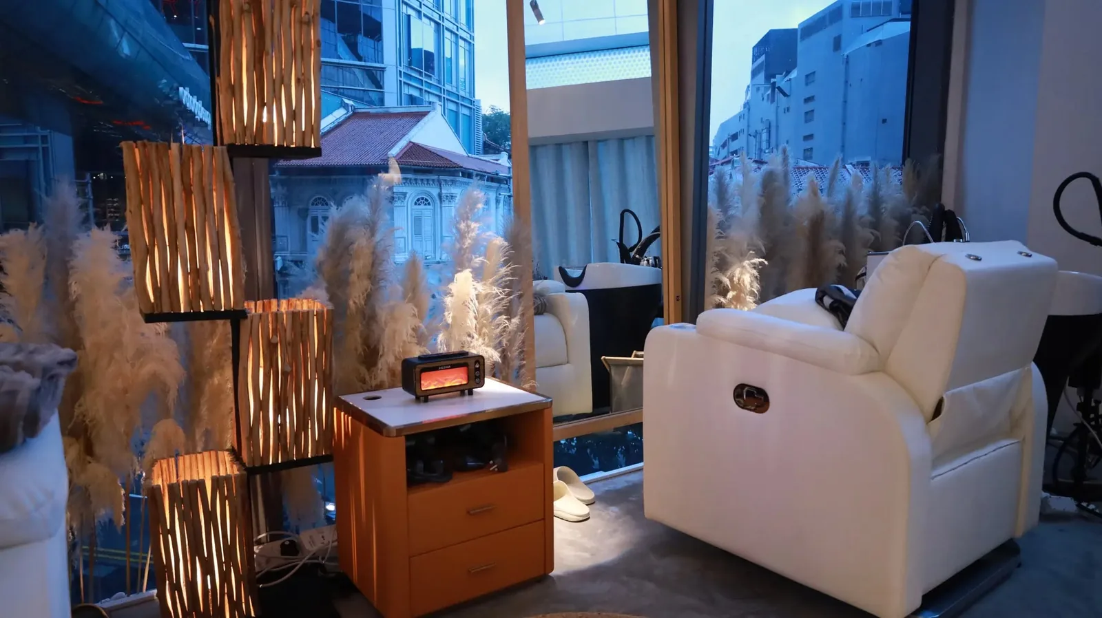Spa treatment room with white reclining chairs, wooden partitions, and city views