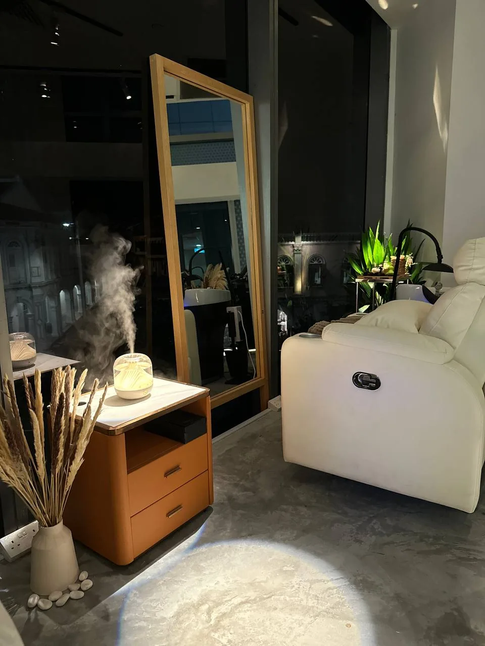 Spa treatment room with white chair, wooden vanity mirror, and ambient lighting