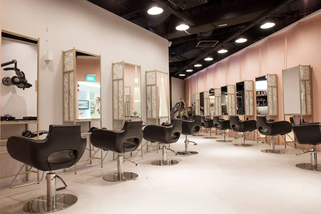 Hair salon interior with black styling chairs, illuminated mirrors, and modern decor