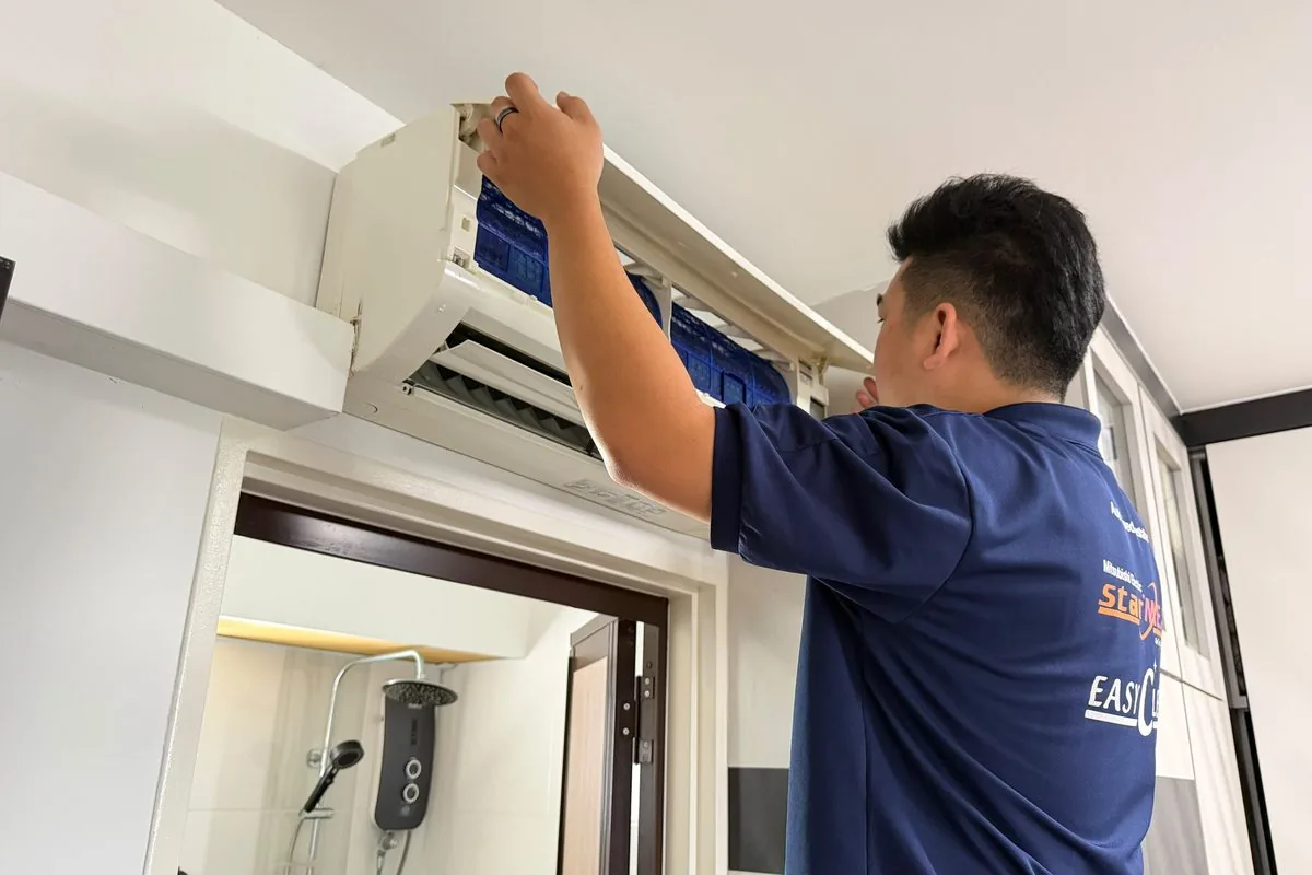 Technician servicing wall-mounted air conditioner unit in home