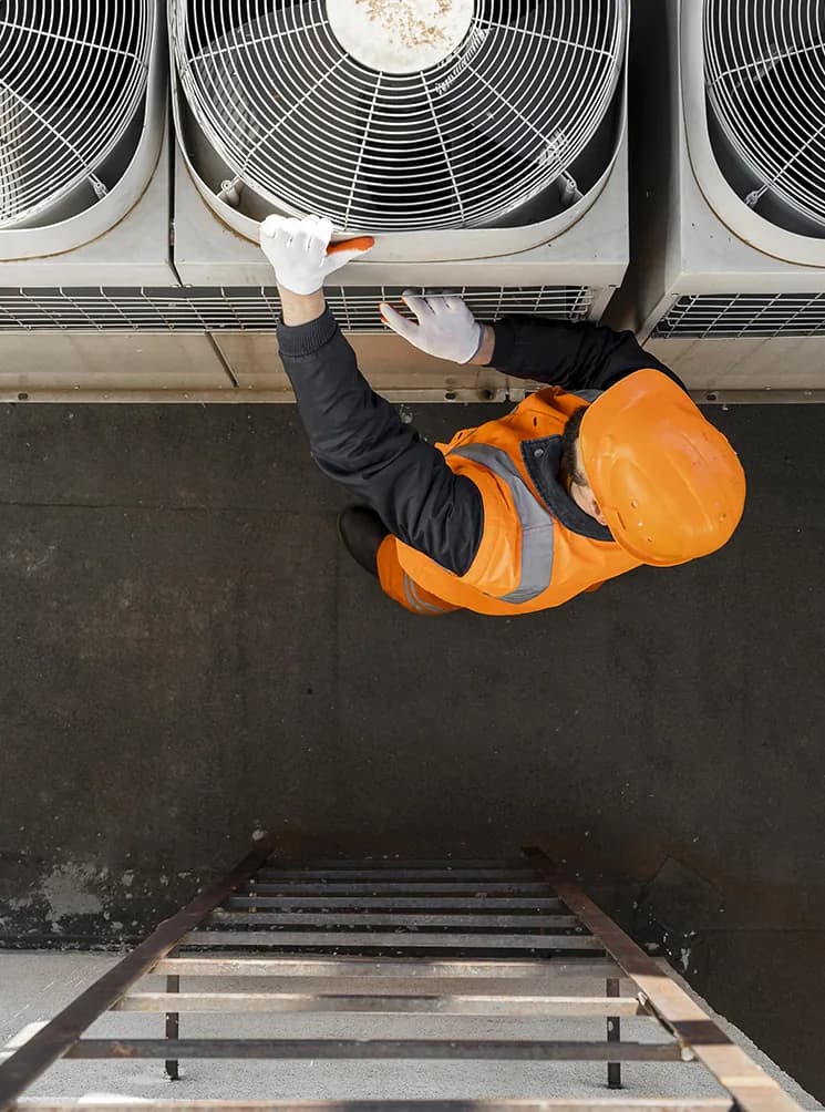 Technician servicing commercial air conditioning units on a roof
