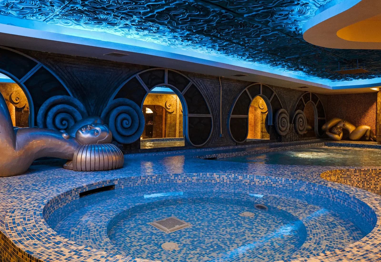 Spa pool area with blue mosaic tiles, bronze sculptures, and ornate blue architectural features