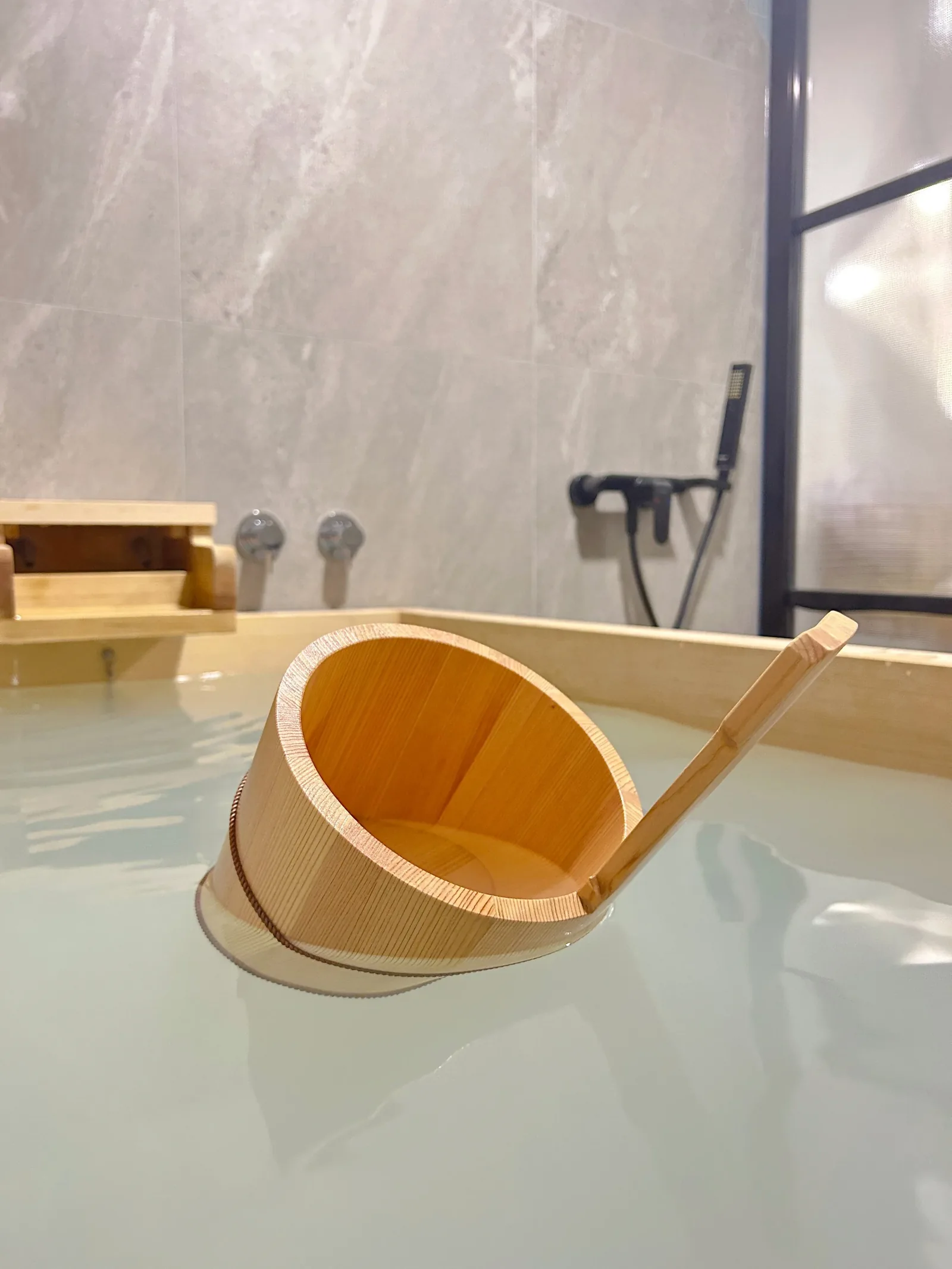 Wooden massage bucket and ladle in a bath at traditional Thai spa