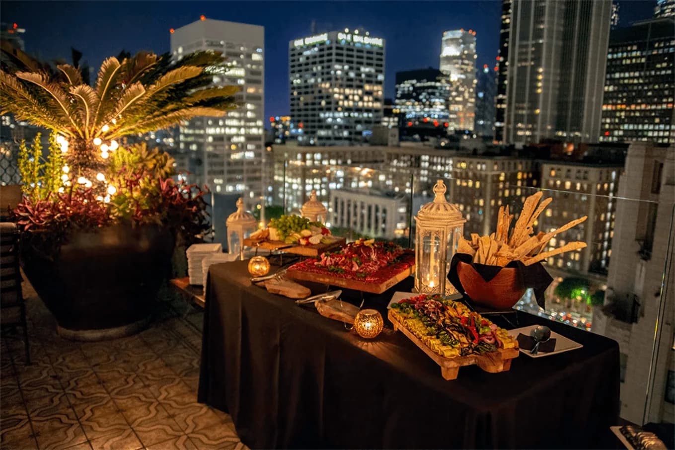Rooftop charcuterie display with city lights and skyline backdrop at evening