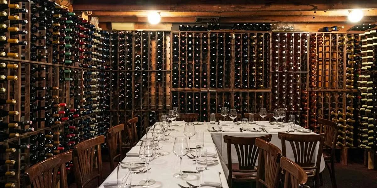 Wine cellar dining room with bottles stored on wooden racks and a formally set table