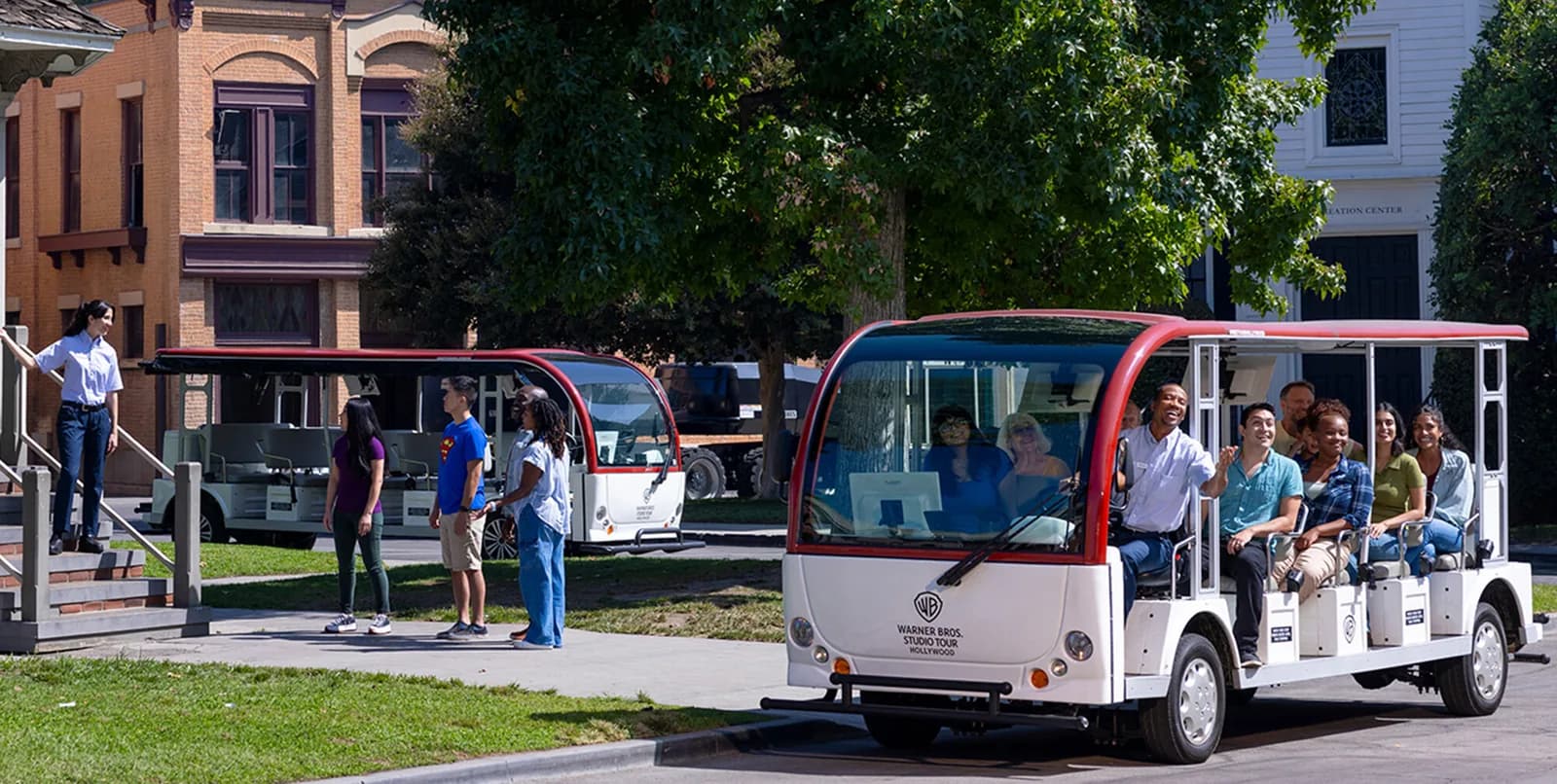 Open-air tour tram with passengers driving through studio grounds near brick buildings