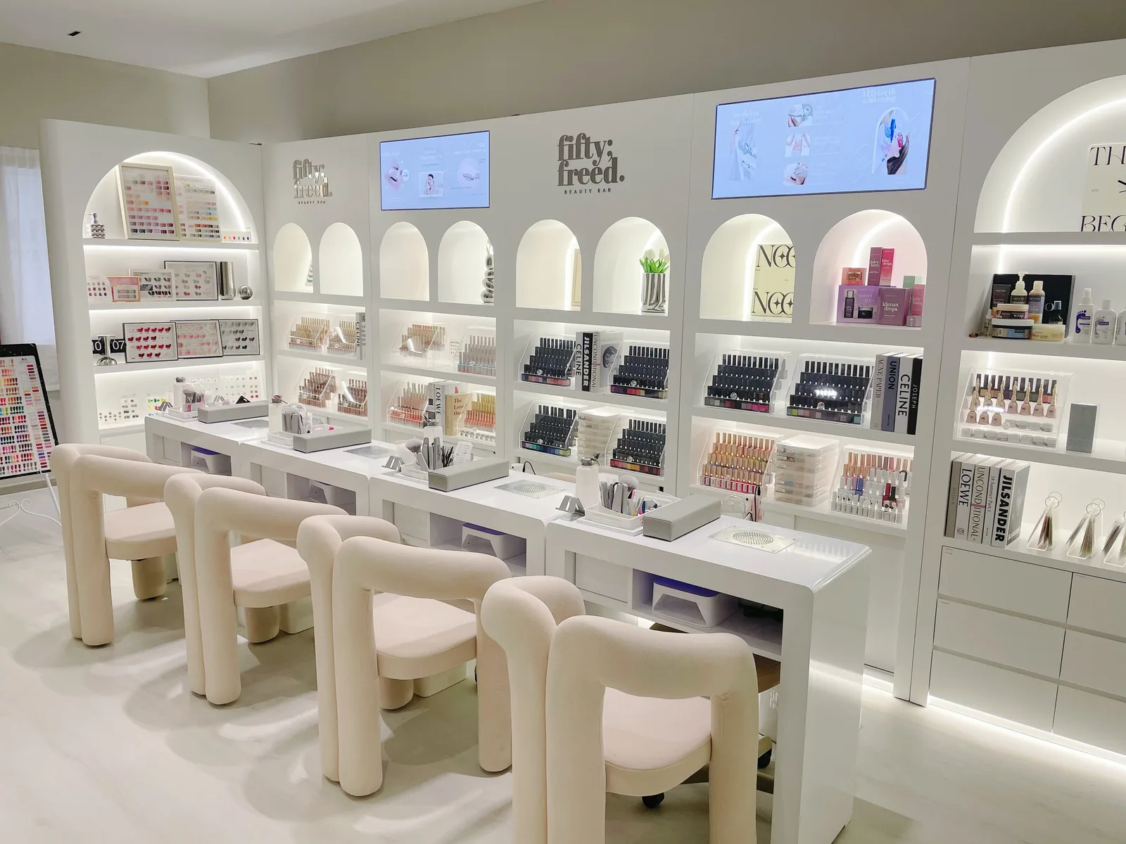Modern beauty salon interior with white cabinetry, product displays, and client seating stations.