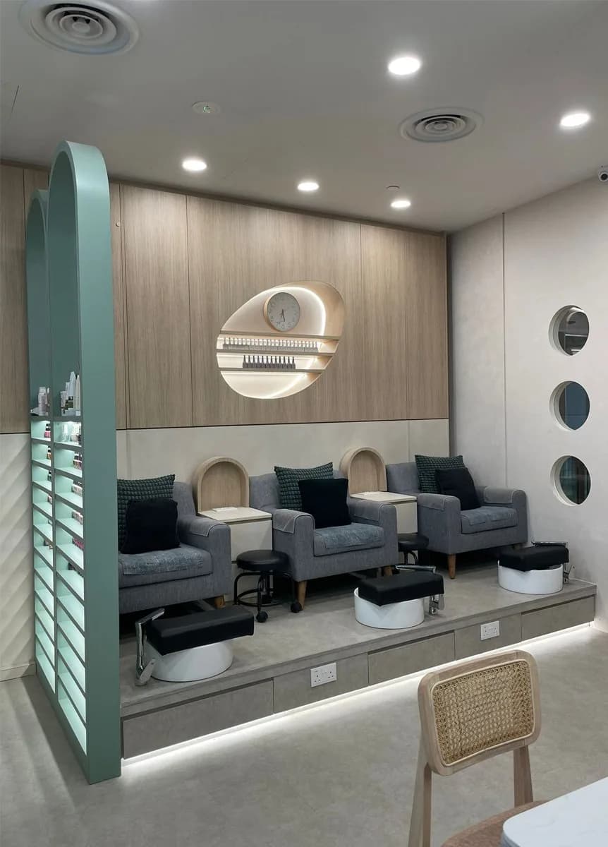 Modern pedicure station with gray upholstered chairs and white footbaths in a contemporary nail salon