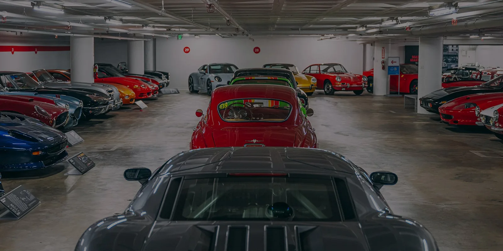 Classic cars displayed in museum garage with red, blue, and black vehicles lined up