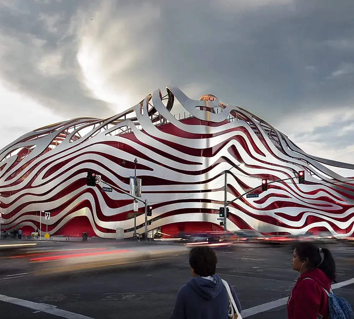 Petersen Automotive Museum's iconic wavy striped facade in red and white against a cloudy sky