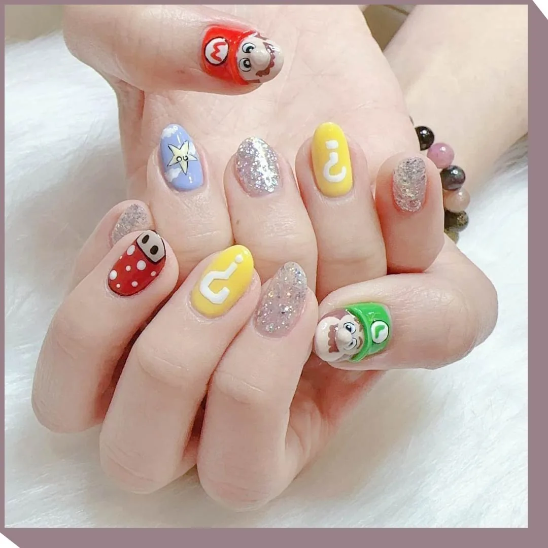 Manicured nails displaying colorful character-themed nail art designs with glitter and cartoon motifs