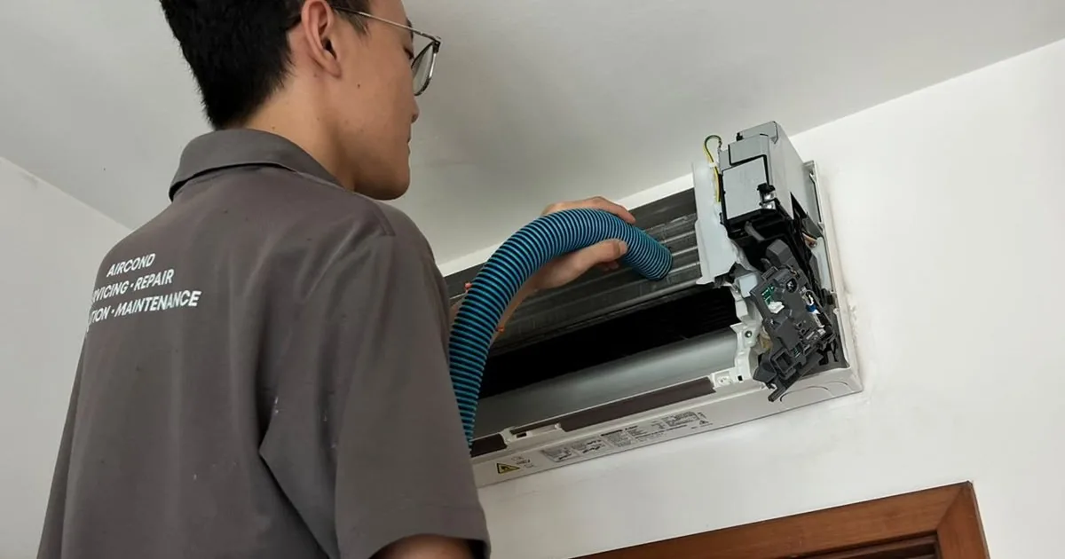 Technician servicing wall-mounted air conditioning unit indoors