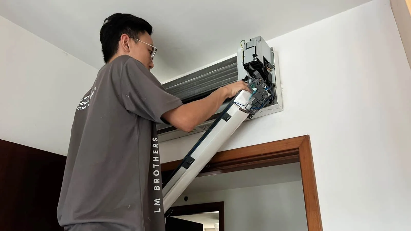 Technician servicing an air conditioning unit mounted on a wall