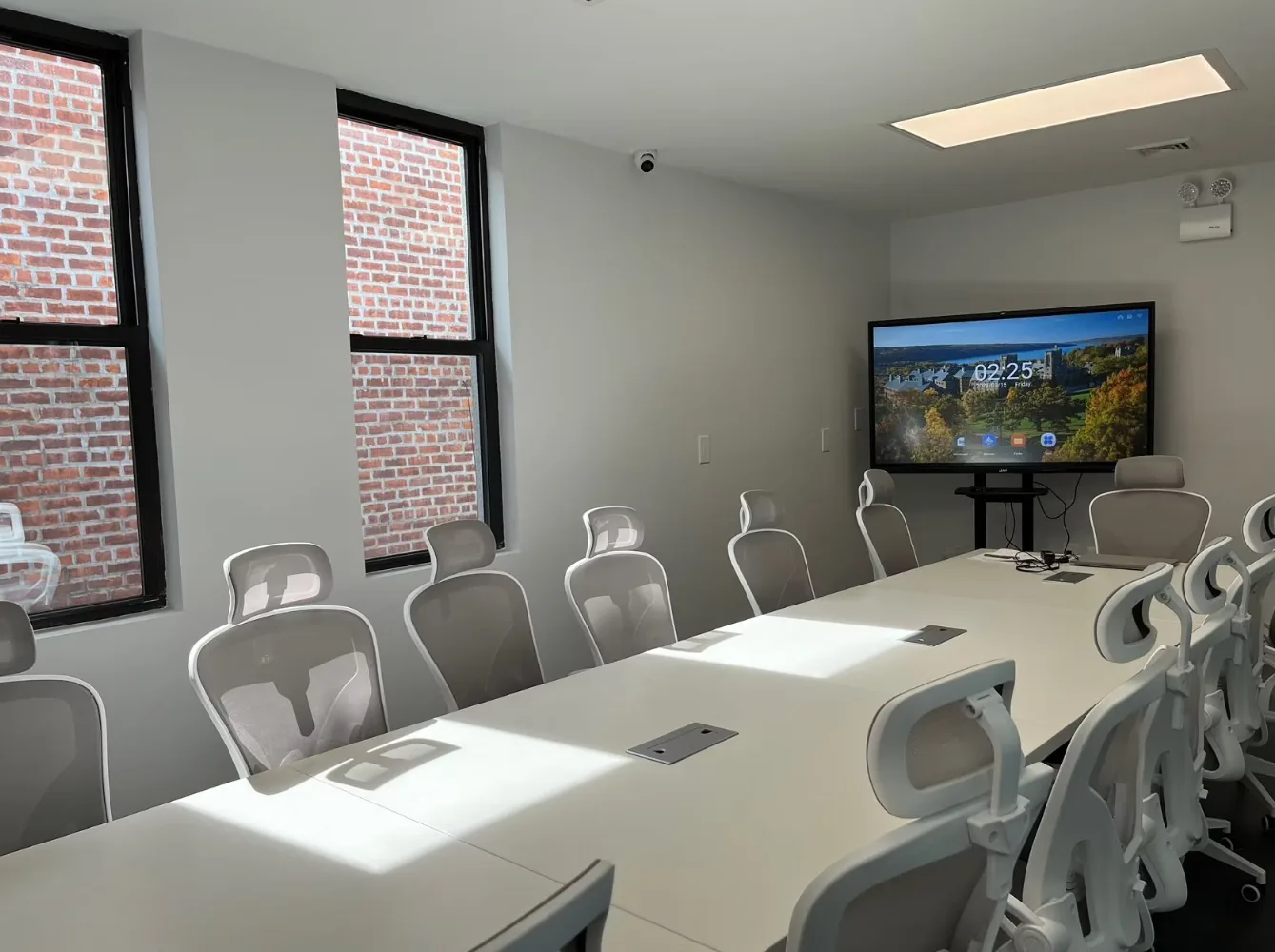 Modern conference room with long table, gray chairs, and mounted screen for tutoring or meetings