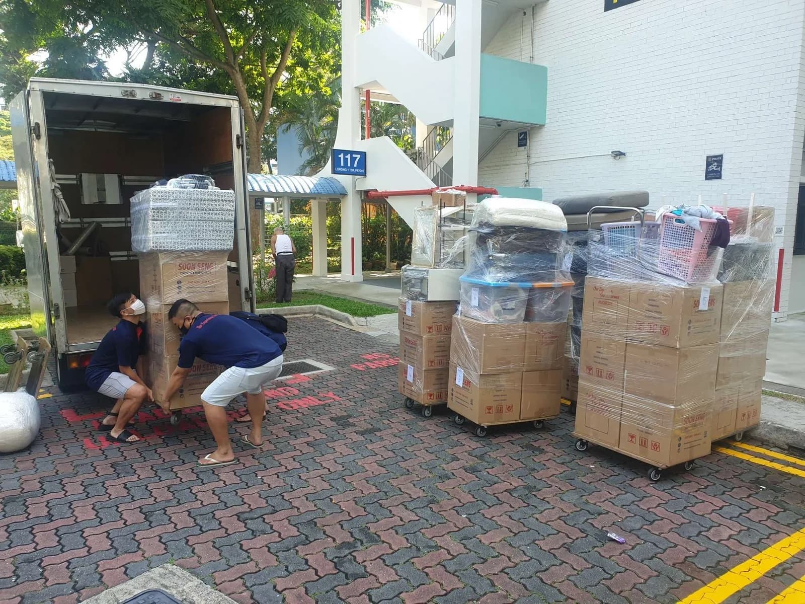 Movers in blue uniforms loading wrapped furniture and cardboard boxes into a moving truck