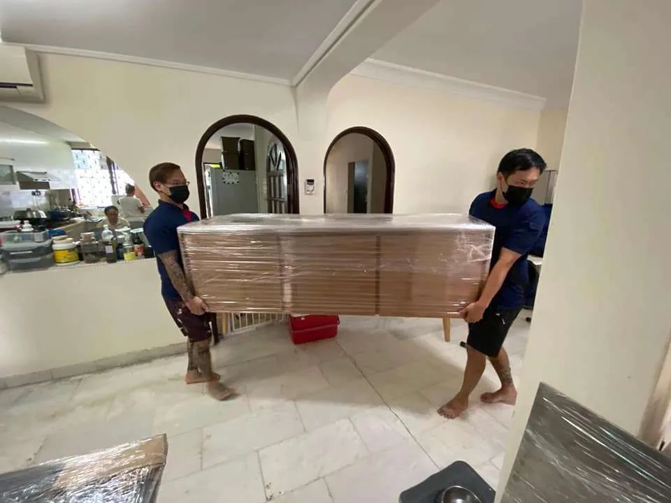 Movers carrying wrapped furniture through modern interior with arched doorways
