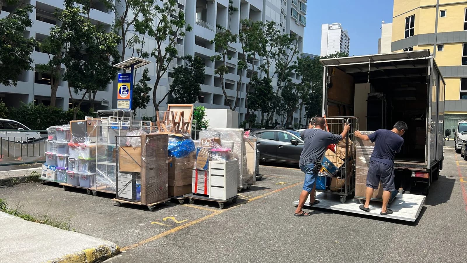 Moving workers loading packed boxes and furniture into a truck at a residential area